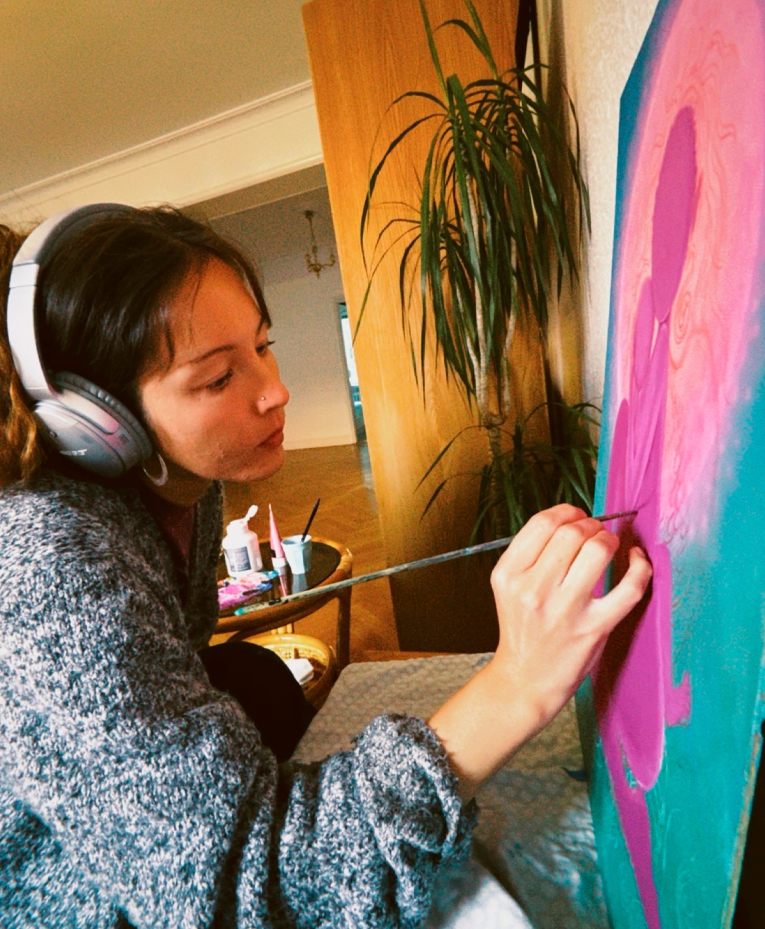 Norea painting a canvas with headphones on